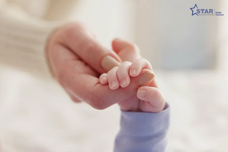 Mother holding her newborn's hand, covered under Star Health maternity benefits